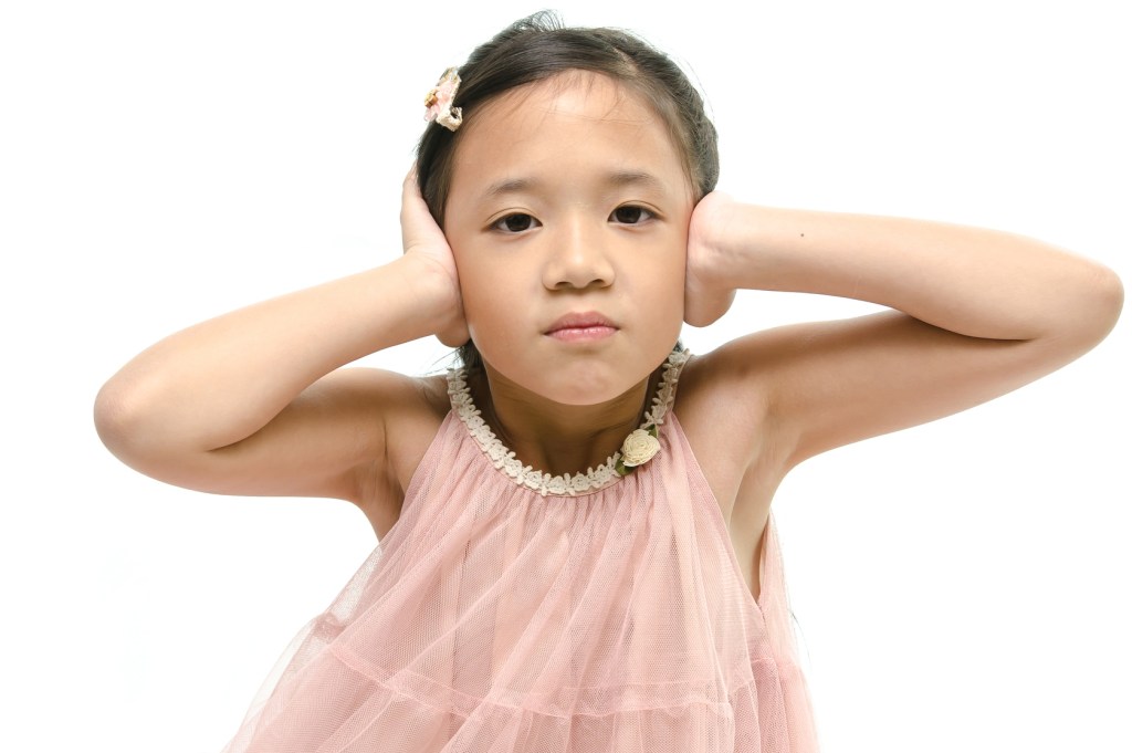 Little girl covering ears while mother scolding