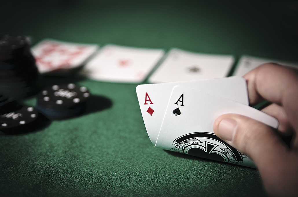 Partida de poker, com cartas e fichas e uma mão.