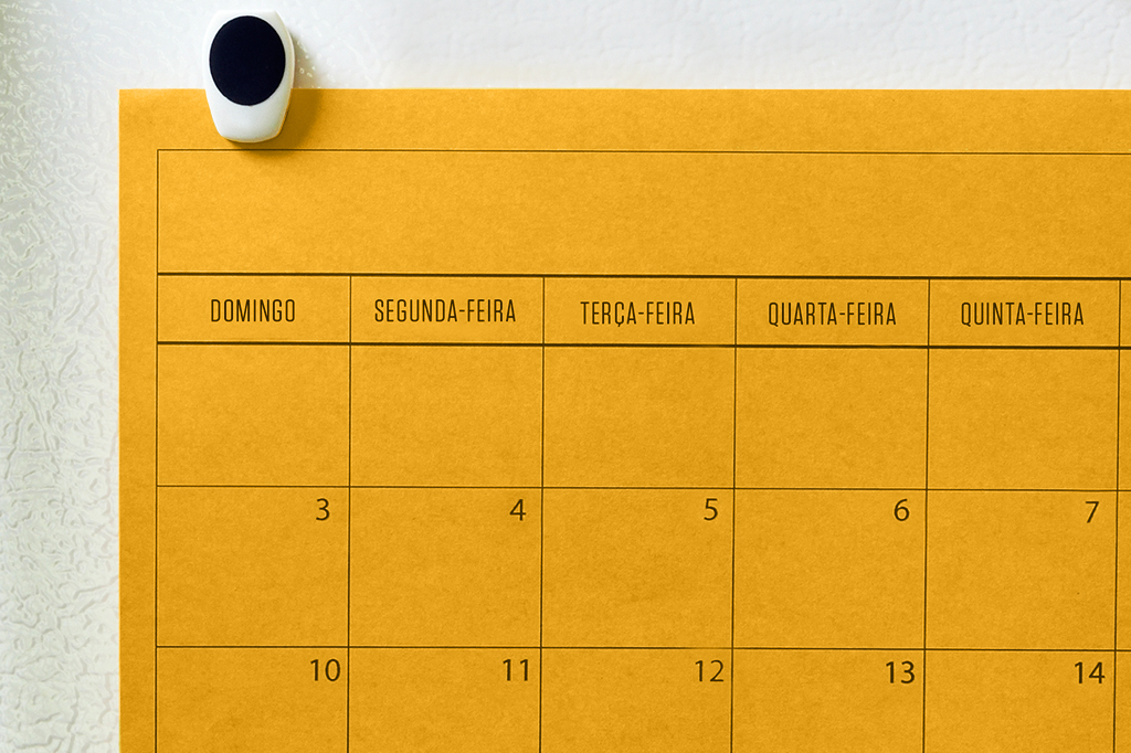 Calendário amarelo preso na geladeira.