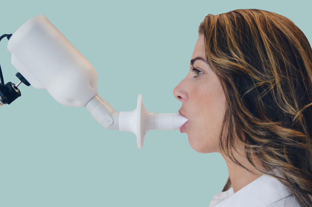 Mulher utilizando o SpiroNose, um bafômetro para detectar Covid-19.