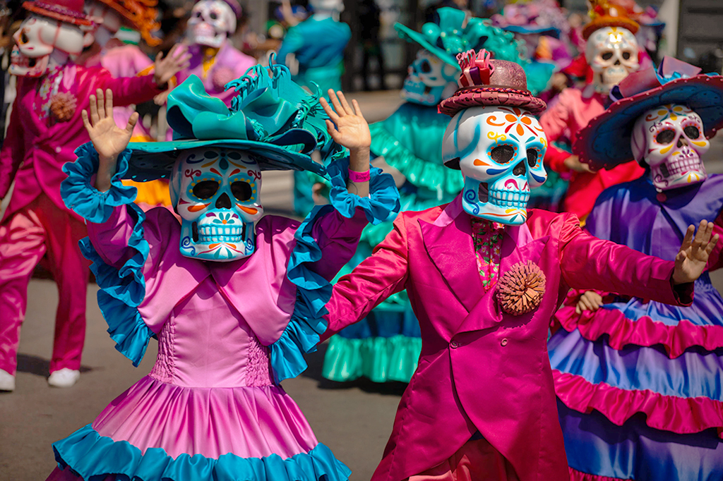 Foto de pessoas com máscaras de caveira e roupas típicas mexicanas no dia dos mortos.