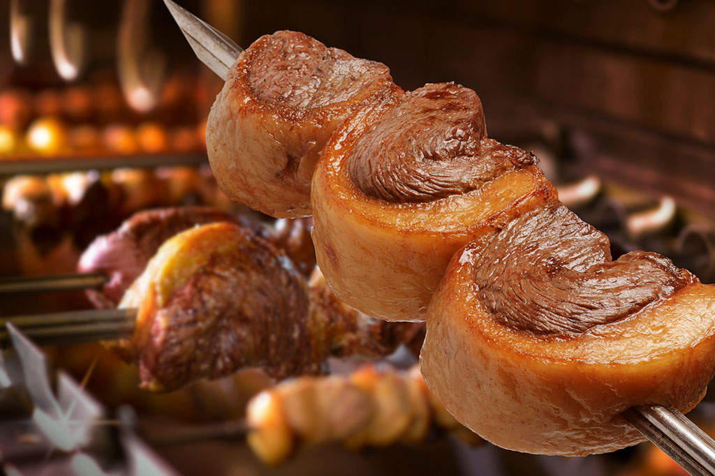 Foto de churrasco picanha assado sobre carvão quente.