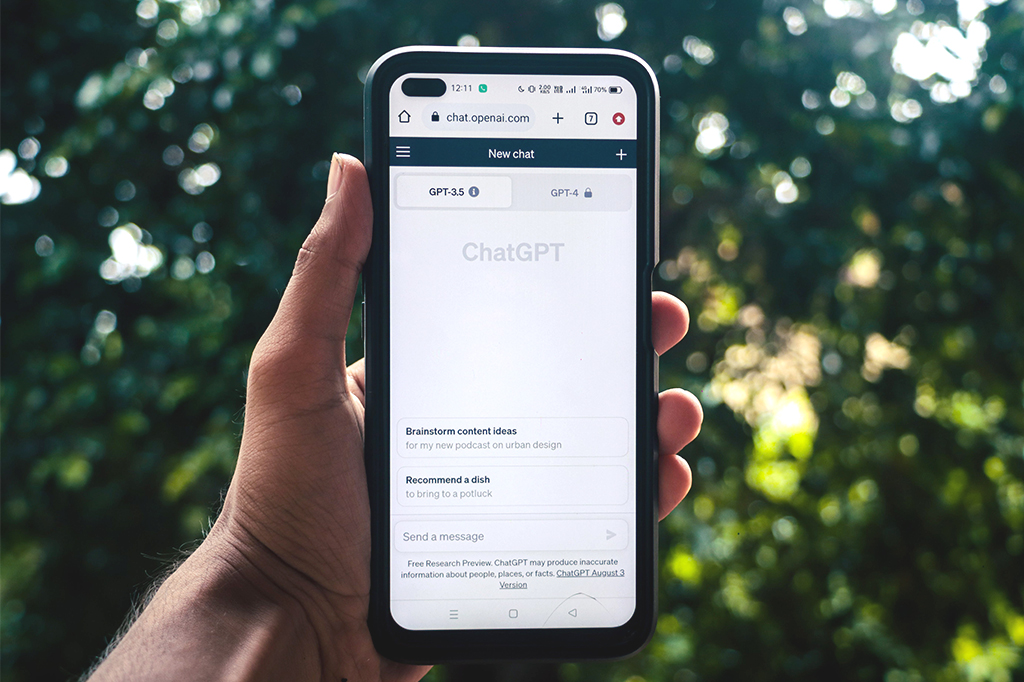 Foto aproximada de uma mão segurando um celular, na tela mostra o início de uma conversa com o Chat GPT.