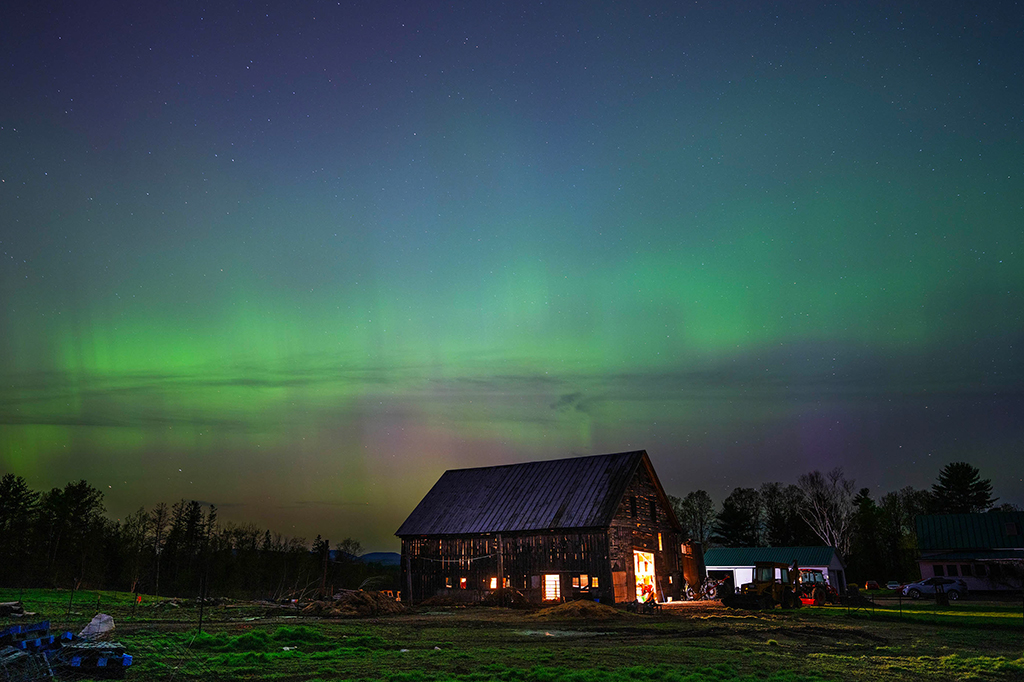 Aurora boreal no céu em um cenário de uma fazenda.