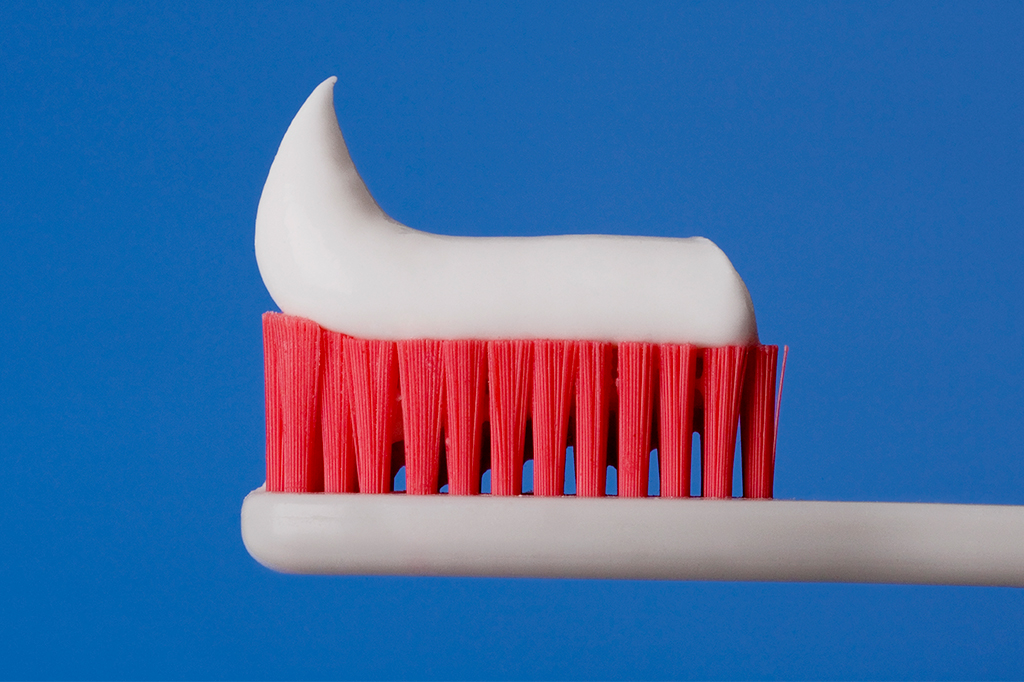 Imagem aproximada de uma escova de dente com pasta em cima.