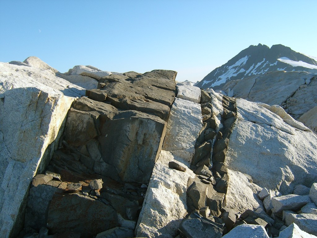 Imagem de paredão de rocha listrado, com rochas pretas e cinza alternadas.