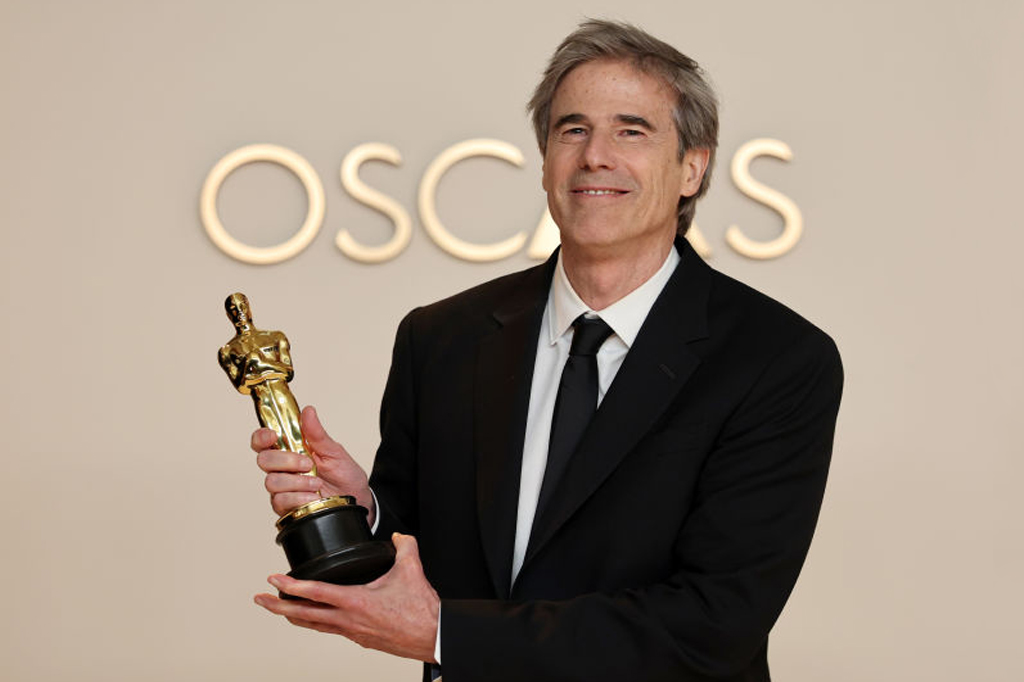 Image de um homem sorridente segurando a estatueta do Oscar.