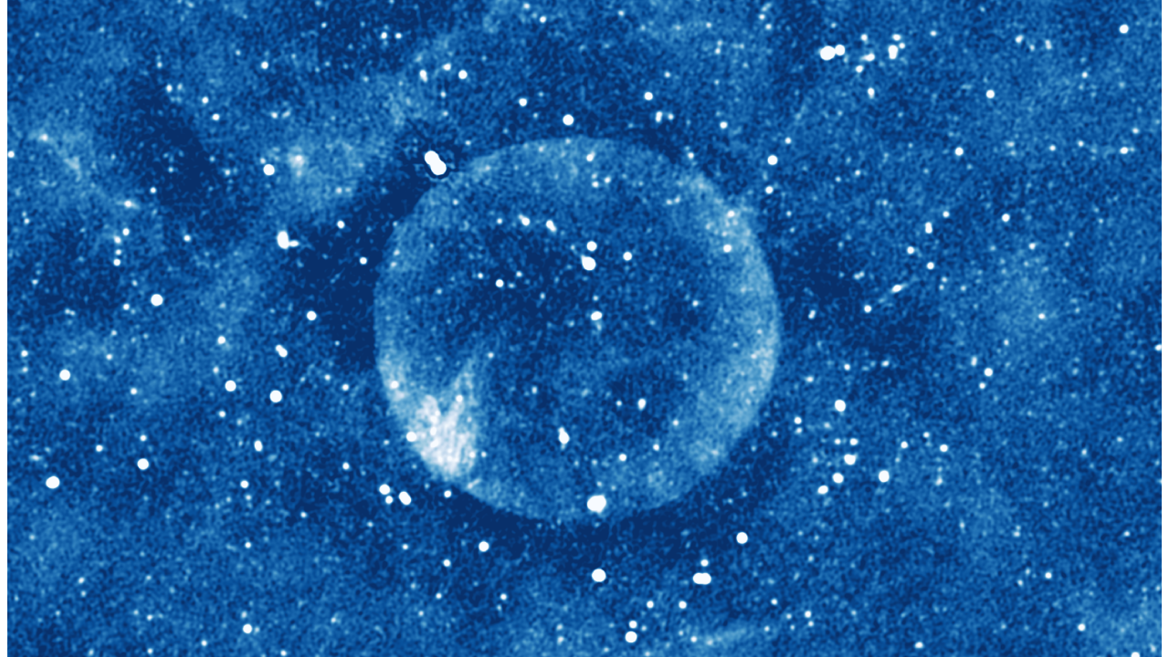 Imagem astronômica azulada, em baixa definição, mostra estrutura cósmica esférica.