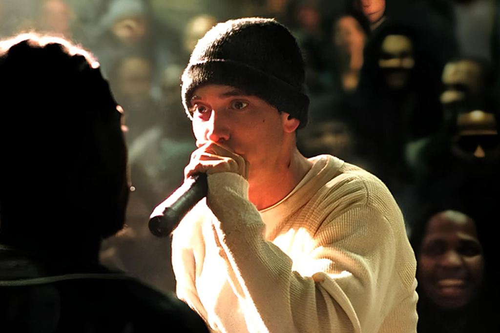 Imagem de um rapaz usando gorro cantando num microfone. Cena do filme 8 Mile (2002).